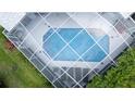 Aerial view of a screened-in pool with surrounding lounge chairs and green grass at 8679 Burning Tree Cir, Seminole, FL 33777