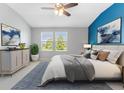 Serene bedroom featuring a soothing blue accent wall, plush bedding, and ample natural light from large windows at 11526 Crowned Sparrow Ln, Tampa, FL 33626