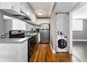 Efficient kitchen featuring stainless steel appliances, white cabinets, hardwood floors, and a convenient washer and dryer setup at 1301 S Howard Ave # A22, Tampa, FL 33606