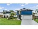 Charming two-story home with a vibrant blue accent and lush landscaping at 15609 Gardenside Ln, Tampa, FL 33624