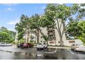 A multi-story condo building with mature trees, balconies, and ample parking at 2699 Seville Blvd # 207, Clearwater, FL 33764