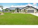Charming single-story home features a well-manicured lawn, lush landscaping, and a neutral color palette at 27466 Tierra Del Fuego Cir, Punta Gorda, FL 33983