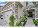 A charming home entrance features stone accents, manicured landscaping, and a welcoming double-door entry at 32490 Tree Of Life Ave, Wesley Chapel, FL 33543