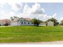 An inviting exterior view of a light blue single-story house with a lush green lawn and palm trees in the front yard at 4959 Cromey Rd, North Port, FL 34288