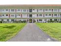 Condo building with a gray entryway path, white facade, red accents, and landscaped green lawn at 5728 14Th N Ave # 101B, St Petersburg, FL 33710
