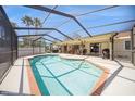 Backyard view of the refreshing screened-in pool, surrounded by a sunny patio with palm trees and lounge seating at 6503 Santiago Ct, Apollo Beach, FL 33572
