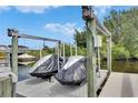 A boat lift on a canal with two boats covered by dark gray tarps at 6512 Simone Shores Cir, Apollo Beach, FL 33572