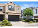 Lovely townhome showcasing a pristine dark two-car garage, and mature tree in the yard at 6711 Rocky Park St, Tampa, FL 33625