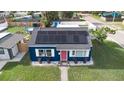 Aerial view of a blue home with solar panels, a pink door, and a well-maintained yard at 1001 57Th N Ave, St Petersburg, FL 33703