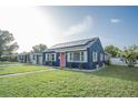 Charming blue home with solar panels, a pink door, white trim, and a green lawn at 1001 57Th N Ave, St Petersburg, FL 33703