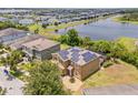 Aerial view of a suburban home featuring a solar panel roof, screened pool, and backyard overlooking a pond at 12244 Fairlawn Dr, Riverview, FL 33579