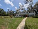 Charming two-story home with a manicured lawn, a red door and mature trees at 210 Kingsway Dr, Temple Terrace, FL 33617