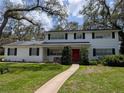 Charming two-story home with a manicured lawn, a red door and mature trees at 210 Kingsway Dr, Temple Terrace, FL 33617