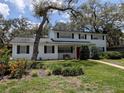 Charming two-story home with a manicured lawn, a red door and mature trees at 210 Kingsway Dr, Temple Terrace, FL 33617