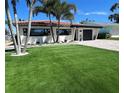 Beautiful waterfront home with manicured lawn, brick driveway, and lush tropical landscaping at 241 176Th Terrace E Dr, Redington Shores, FL 33708