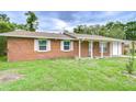 The red brick home features white trimmed windows with an expansive green front yard at 40019 Pretty Redbird Rd, Zephyrhills, FL 33540
