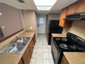 Bright kitchen area featuring black range and refrigerator, light countertop, and wooden cabinetry at 5042 Terrace Village Ln, Tampa, FL 33617