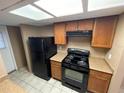 Galley kitchen featuring a black refrigerator and range, plus light countertops and wooden cabinetry at 5042 Terrace Village Ln, Tampa, FL 33617