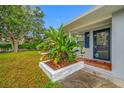Close up view of the front door and beautifully landscaped flower bed with tropical plants at 538 Bamboo Ln, Clearwater, FL 33764