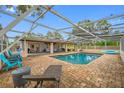 Relaxing screened-in pool area featuring a beautiful brick patio and comfortable lounge furniture at 538 Bamboo Ln, Clearwater, FL 33764