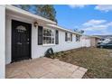The front of the home is captured from an angle showing the front door, front windows, and an unlandscaped yard at 8401 Pinewood St, Tampa, FL 33615
