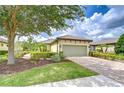 Charming home featuring a tile roof, two-car garage, brick paver driveway, and lush landscaping at 8433 Alberata Vista Dr, Tampa, FL 33647