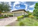 Charming home featuring a tile roof, two-car garage, brick paver driveway, and lush landscaping at 8433 Alberata Vista Dr, Tampa, FL 33647