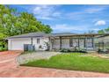 Back of home with a screened in lanai, white painted brick and lush landscaping at 9615 Raiden Ln, Riverview, FL 33569