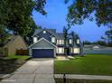 Charming two-story home with a well-manicured lawn and mature trees at dusk at 10208 Evening Trail Dr, Riverview, FL 33569