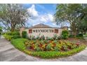 Weymouth community entrance featuring a decorative wall and colorful flower beds at 19204 Weymouth Dr, Land O Lakes, FL 34638