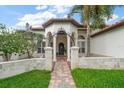 Beautiful home entrance with a brick pathway, stone columns, and a landscaped yard at 307 Palmetto Ln, Largo, FL 33770