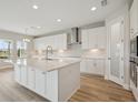 Bright kitchen with an island, white cabinets, quartz countertops, and modern stainless-steel appliances at 3483 Yellow Leaf Cir, Spring Hill, FL 34609