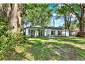 View of the home nestled among mature trees, boasting a green lawn, and classic architectural details at 3615 Greatwood Ct, Land O Lakes, FL 34639