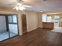 Open-concept living room with wood floors leading into the kitchen and sliding door to the outdoor porch at 4111 Ashford Green Pl # B203, Tampa, FL 33613