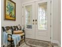Elegant foyer with decorative glass double doors, a stylish bench, and a tasteful area rug at 4973 Antiquity Way, Sarasota, FL 34240