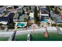 Beachfront property featuring a private beach, boat dock, and neighboring homes with swimming pools on a sunny day at 7777 Bayshore Dr, Treasure Island, FL 33706