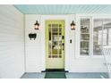 Close-up of the front door of a lovely home with outdoor lanterns and a stylish yellow door at 106 W Minnehaha St, Tampa, FL 33604