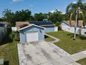 A cozy blue house with a one-car garage and solar panels, complete with a neatly paved driveway at 11521 Paperwood Pl, Riverview, FL 33579