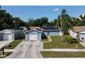 A quaint blue house showcases solar panels, a one-car garage, and a tidy front yard, offering suburban charm at 11521 Paperwood Pl, Riverview, FL 33579