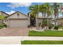 Inviting home with well-manicured lawn, palm trees, and a brick driveway leading to a two-car garage at 12026 Crestridge Loop, New Port Richey, FL 34655