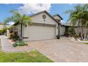 A spacious garage with a brick-paved driveway and meticulously maintained landscaping in a serene neighborhood at 12026 Crestridge Loop, New Port Richey, FL 34655