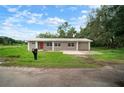 Attractive single-story home with a red door, a metal roof, an attached garage, and a large front yard at 1217 W Terrace Dr, Plant City, FL 33563