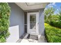 Close-up of the front door with a screen door and a small porch area with decorative landscaping at 13636 Lake Point S Dr, Clearwater, FL 33762