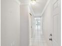 Bright hallway featuring white tile flooring and walls, leading to an open living space with natural light at 13636 Lake Point S Dr, Clearwater, FL 33762