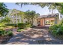 Elegant two-story home with a covered parking area and a lush, landscaped front yard with mature trees and flowering shrubs at 15612 Howell Park Ln, Tampa, FL 33625