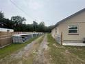 View of the house's exterior with a gravel driveway and a long row of metal fencing panels at 18133 Us Highway 41, Spring Hill, FL 34610