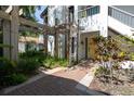 Beautiful home exterior featuring a yellow door, brick walkway, pergola, and lush landscaping at 1854 Lake Cypress Dr # 1854, Safety Harbor, FL 34695