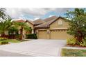 The house features an attached three-car garage with decorative windows, side coach lights, and manicured shrubbery at 20023 Pergola Bend Ln, Tampa, FL 33647
