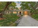 Charming single story home featuring a well maintained lawn, lush trees, and a private carport at dusk at 4309 W Empedrado St, Tampa, FL 33629
