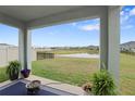 View from covered back porch shows large backyard, pond, and neighboring homes in the Silverstone community at 5214 Granite Dust Pl, Palmetto, FL 34221